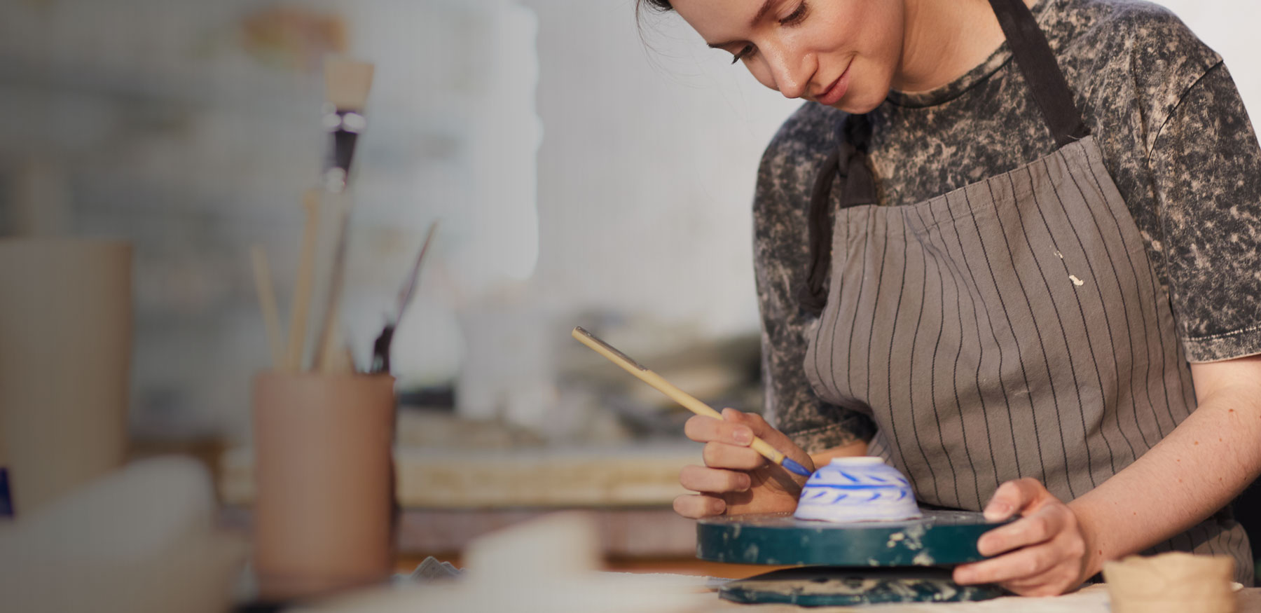 woman painting clay pot